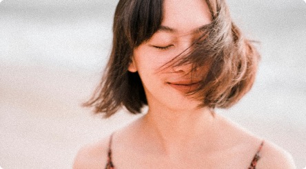 A woman with her eyes closed, hair caught in the wind